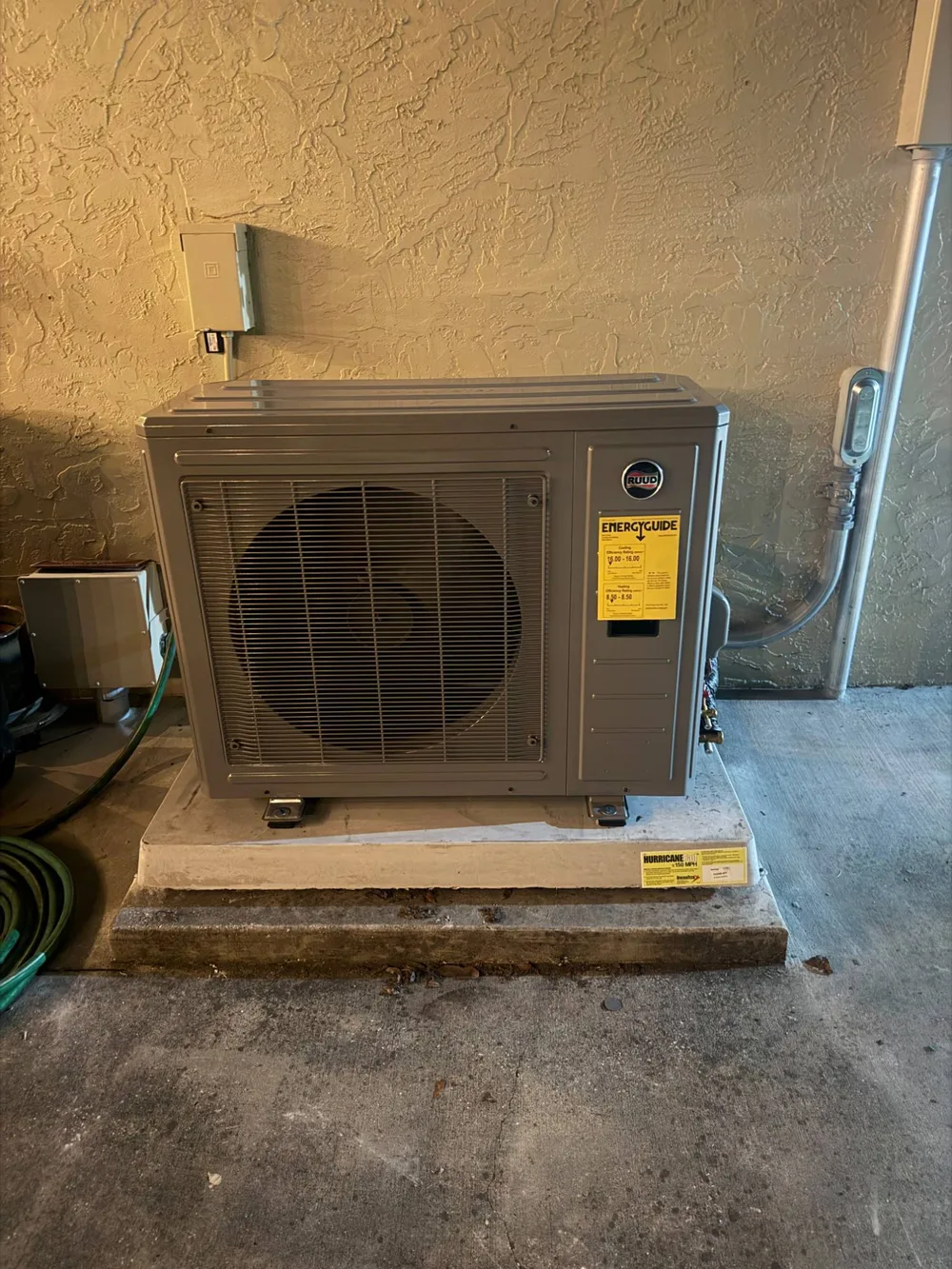 New Ruud outdoor heat pump unit on a hurricane-rated pad in a Wesley Chapel home